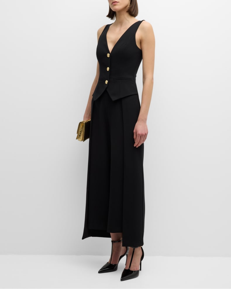Model dressed in a black Irene Sleeveless Wide-Leg Jumpsuit, paired with black heels and a gold clutch